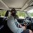 Pixelated static image shows two figures in a vehicle interior with green and gray tones, one figure holding a steering wheel, background includes blurred windows and ceiling.