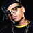 Pixelated image of a person with light skin, brown hair styled in an updo, wearing dark sunglasses and a yellow garment against a black background.