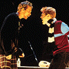 Animated sequence showing two figures in dark clothing with maroon and light blue accents, interacting at a table with white cylindrical objects, while text changes from 'con' to 'connection' across frames.