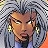 Pixelated portrait of a person with light brown skin, dark eyes, and a neutral expression, wearing large circular earrings and a blue garment against a checkered background.