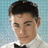 Pixelated image of a person with dark hair and a white shirt with a black bow tie on a light blue background, with blue text elements.