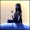 Animated sequence of a figure with long dark hair holding a small object, seated on a blue rounded base against a shifting light background.