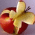 A pixelated image of a sliced apple with visible core and stem, set against a muted purple background.