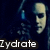 A pixelated image of a person with long dark hair holding a blue bottle, showing text overlays and partial gray background.