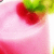 Pixelated image of a red fruit with green top on pink background, likely cherry or strawberry.