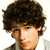 Pixelated close-up of a person with dark curly hair, light skin tone, and visible facial features including eyes, nose, mouth, and ear against white background.