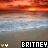 A pixelated sunset over water with 'BRITNEY' text in contrasting color schemes and small heart icons on either side.