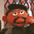Pixelated cartoon character with red skin, black hair, and a wide open mouth in an exaggerated expression against a blurred background.