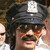 A person wearing a dark police-style cap with a white badge, mustache, and sunglasses appears in four showing slight variations