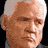 Static image with red text on black background featuring a partial headshot of a man with gray hair and serious expression.