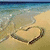 Beach scene with heart drawn in sand, water, and text overlay reading 'I wish he knew that he's all I think about' on the left