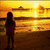 Silhouette of a person standing on a beach at sunset with a bright sun and orange-yellow sky reflecting on water.