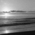 A grayscale landscape with horizontal bands of varying brightness, featuring a bright light source in the upper left and dark lower sections.