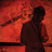 Pixelated red-toned image of a figure in dark clothing holding a glowing object against a fiery background.