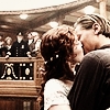 A static image shows two people kissing in a courtroom setting with a judge and audience in the background.
