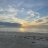 Static pixelated image of a coastal scene with water, sand, and sky under scattered clouds.