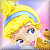 Pixelated cartoon-style icon of a blonde character with blue eyes and pink lips, wearing a light blue headband, holding a golden object against a pastel background.