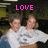 Two people in white shirts with a circular logo hug, pink 'LOVE' text appears above them