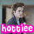 Pixelated image of a person with brown hair wearing dark clothing, standing in front of an interior background with text reading 'hottie' at the bottom.