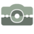 Pixelated icon of a camera with light green top and dark green bottom, featuring a circular lens design in the center.