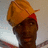 A static image with a red background, yellow text, and a pixelated photo of a person wearing a yellow cap and red headband.