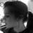 Black-and-white pixelated image of a person's profile with dark hair, visible ear, and partial facial features including an eye and mouth.