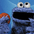 Pixelated image of two characters: a large blue figure with wide eyes and an open mouth, and a smaller orange-haired character on the left.