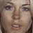 Pixelated close-up of a person's face showing eyes, nose, mouth, and hair with brown and beige tones.