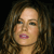 Static pixelated image of a person with long brown hair, light skin, and pink lips, cropped to show the head and upper shoulders against a dark background.