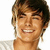 A person with light brown hair and a white shirt smiles broadly against a plain background.