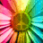 A vibrant, pixelated flower with radiating petals in pink, yellow, green, and cyan hues arranged in a circular pattern.