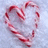 A heart-shaped arrangement of red-and-white striped candy canes on a light blue background, next to green text reading "i luv christmas" in pixelated font.