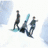 Animated sequence showing three figures on a snowy slope with one figure sliding down, another standing, and the third in mid-action pose.