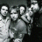 Pixelated grayscale image of multiple stylized human figures in a group pose with varying facial features and body positions against dark background.