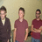 Three pixelated figures stand side-by-side against a light brown background, wearing dark and maroon shirts with visible facial features and hair.
