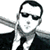 A 50x50 pixel animated buddy icon featuring a stylized figure in sunglasses and suit on the left frame, transitioning to a green-tinted weapon-like object on the right frame.