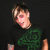 Pixelated image of a person with light skin and brown hair wearing a dark shirt featuring green abstract patterns against a black background.