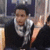 Pixelated image of a person in dark clothing with light-colored shirt, extending an arm toward the viewer against a blurred background.