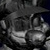 Pixelated grayscale image of a character with a wide mouth and large eyes, wearing a dark hat and light-colored clothing against a dark background.