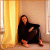 A woman in black clothing sits on a floor against a wall with a golden curtain, with "I'm Home" text above her and a white plus sign appearing in different positions across frames.