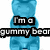 Blue gummy bear figure with stacked text blocks over a white background, partially obscured by a brown circular object with colorful sprinkles.