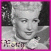 Black-and-white portrait of a woman with styled blonde hair, wearing a white collar and floral accessory, framed by pink border with 'Betty' text.