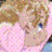 Pixelated image of a person with light brown hair and blue eyes wearing a pink garment against a soft background.