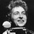Black-and-white pixelated image of a person with closed eyes holding a microphone against a dark background.