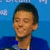 Pixelated portrait of a person with short dark hair wearing a blue top against a solid blue background.
