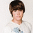 Pixelated image of a person with brown hair wearing a white shirt with a blue graphic, set against a bright pink background with white text elements.