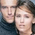 Two people in close proximity, one with light skin and dark hair wearing a dark top against a blurred background.