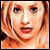 Pixelated static image of a person's face with light brown hair and neutral expression, rendered in warm tones on a dark background.