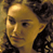 Pixelated static image of a character's face with yellowish skin tone and dark hair against a brown background.