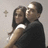 Two figures embrace in a close-up pose against a light gray background with pixelated rendering.